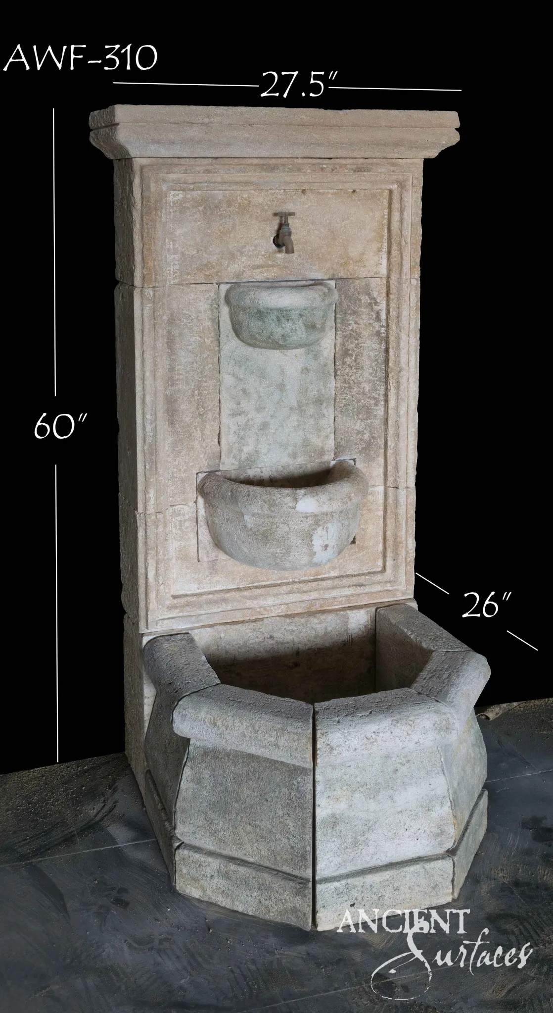 Narrow reclaimed antique limestone wall fountain from Ancient Surfaces with a bronze spigot filling an upper carved lavabo bowl, a smaller semicircular bowl below it and a canted apron basin, the bowls stained soft green